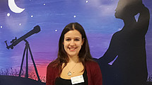 Halbportrait von lächelnder Sabrina Patsch vor Plakat mit Nachthimmel stehend