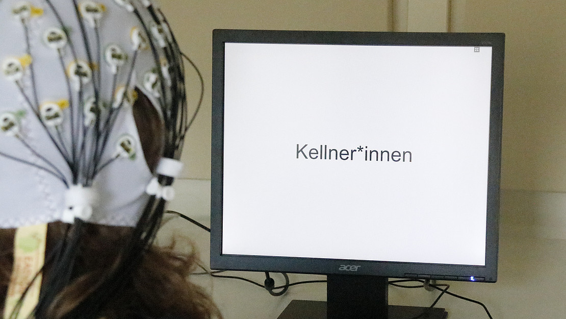 The picture shows a person in front of a computer screen: Electrodes attached to the head were used to measure the electrical activity of the brain when reading different sentence combinations