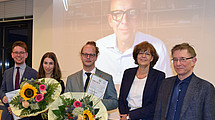 The picture shows from left: Ceremonial award ceremony, from left: Lukas Kiepe (moderator of the evening and jury member), the award winners Sebastian Niemczyk and Mira Bickert, Nicola Behrend (judge at the Federal Social Court and laudator for Sebastian Niemczyk), Prof. Dr. Andreas Hänlein (Chairman of the Association for the Promotion of Research and Knowledge Transfer in Social Law and Social Policy e.V.). In the background: Prof. Dr. Heinz Bude (laudator for Mira Bickert).