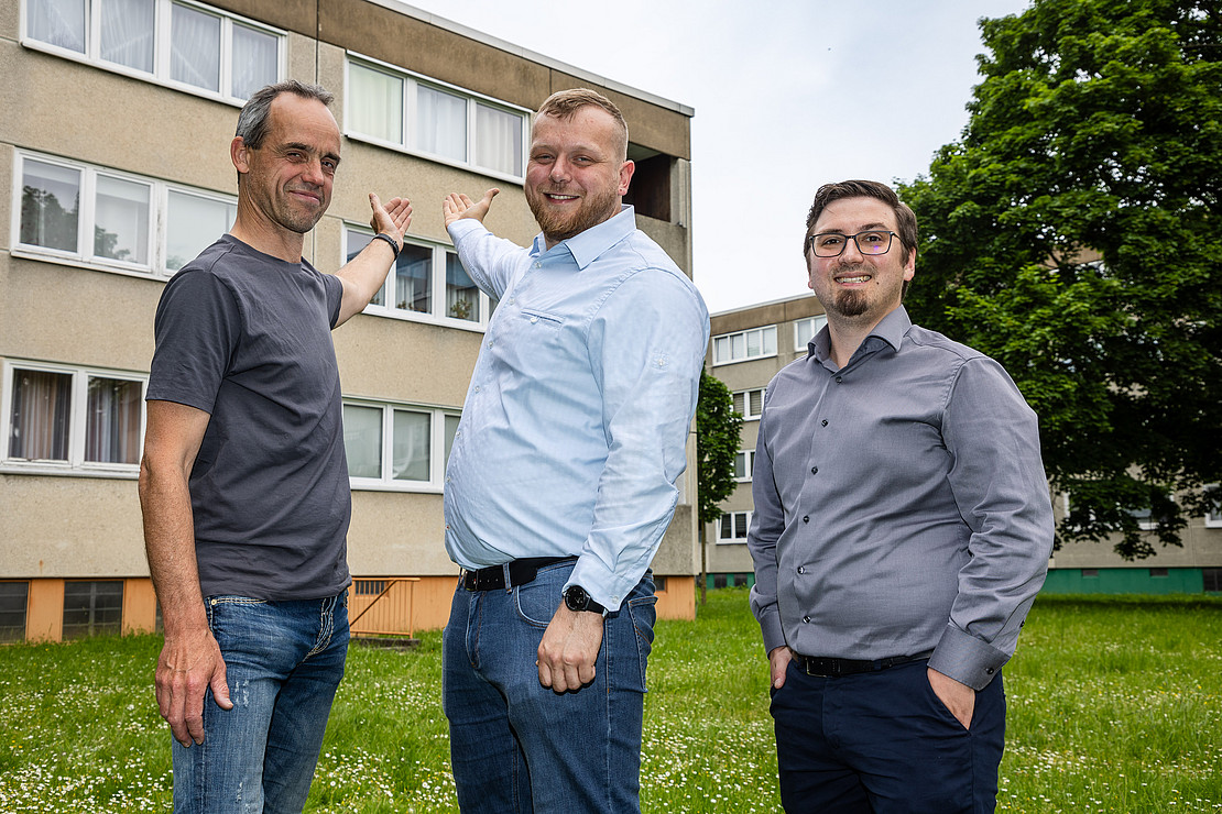 Three men in front of a building. 