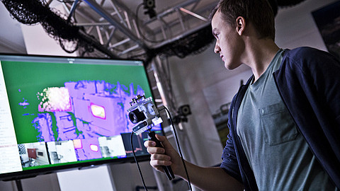  (opens enlarged image)The picture shows a man in the thermography laboratory. He is holding a camera that can detect escaping gas.